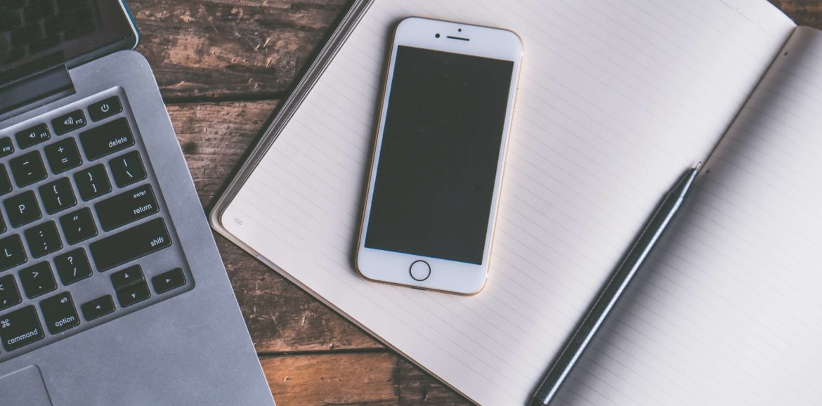 Smartphone, Notizblock und Laptop auf einem Tisch