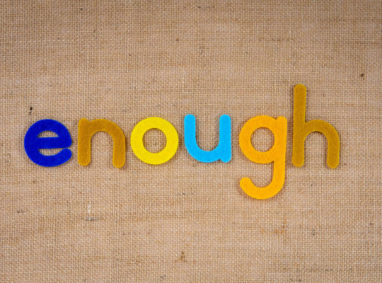 Bunte Stoffbuchstaben, die das Wort "enough" formen auf einem Jutestoff