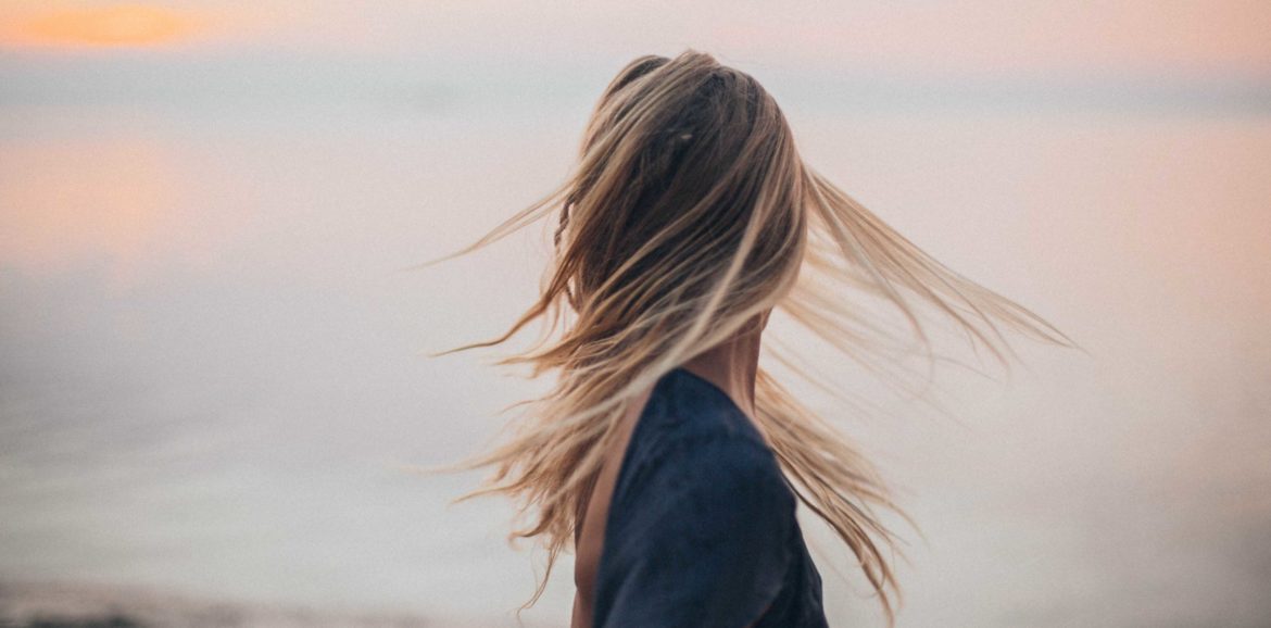 Blonde Frau von hinten, deren Haare im Wind wehen