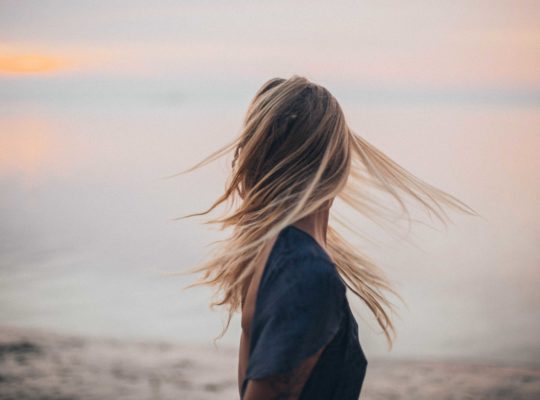 Blonde Frau von hinten, deren Haare im Wind wehen